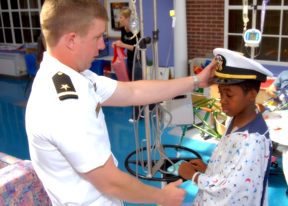 US Navy 090422-N-1522S-005 nsign Brian Stueber, the Administration Officer assigned to Pre-Commissioned Unit (PCU) Truxtun (DDG-103) shares his cover with a child while volunteering at the Medical University of South Carolina C