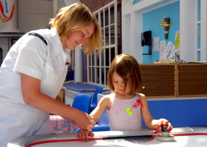 US Navy 090422-N-1522S-006 Engineman Fireman Stacy Carmichael, assigned to Pre-Commissioned Unit (PCU) Truxtun (DDG-103), shares a friendship bracelet with a girl while volunteering at the Medical University of South Carolina