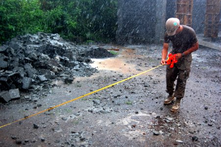 US Navy 090424-N-1057H-449 Engineering Aide Constructionman Travis C. Porter, assigned to Naval Mobile Construction Battalion (NMCB) 11, Detachment Horn of Africa, takes measurements in a rain storm for the Hamramba School Proj photo