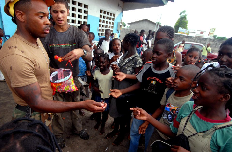 US Navy 090422-N-1688B-424 teelworker 1st Class Kajuna Strickland, left, and Information Systems Technician 3rd Class Cameran Heckenlaible hand out candy to children at the Balise School in Port Gentl during an Africa Partnersh