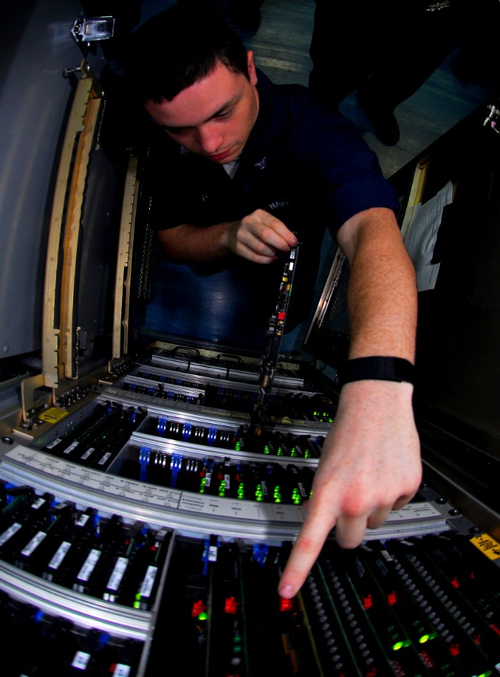 US Navy 090422-N-6597H-053 Electronics Technician 3rd Class Ernesto Deleon, from Salem, Ore., replaces a circuit card assembly in the SSC-12 air traffic control communications system