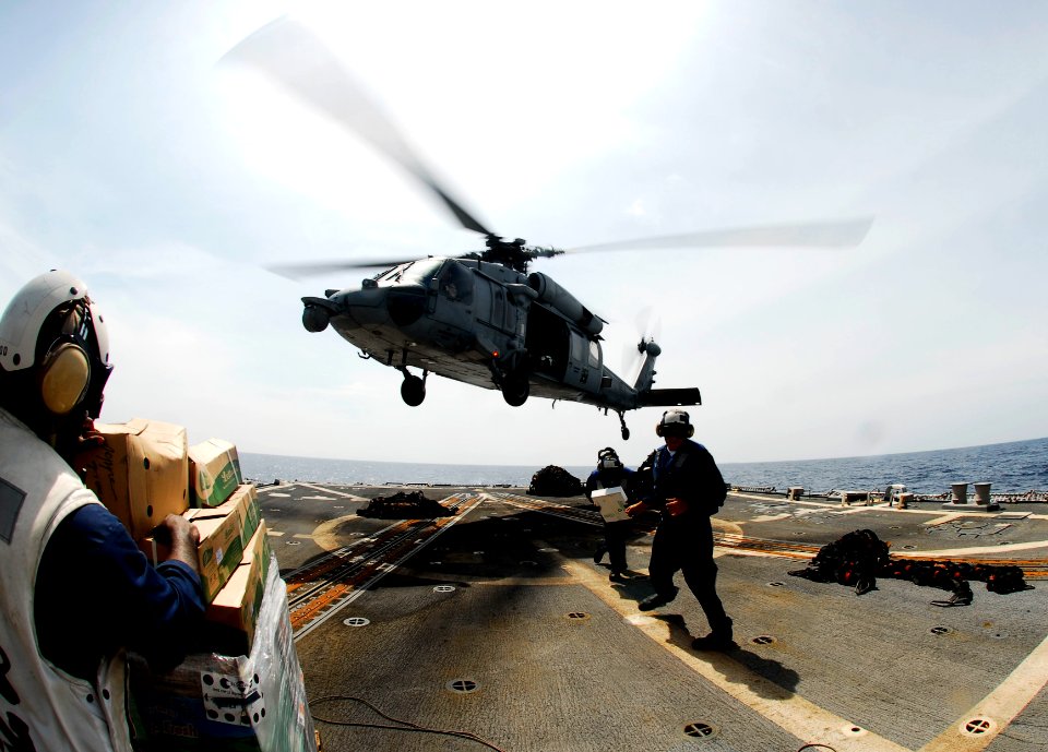 US Navy 090423-N-9928E-242 Sailors carry supplies delivered by an MH-60S Sea Hawk helicopter from the