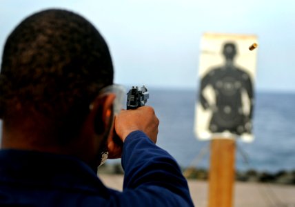 US Navy 090424-N-7280V-262 Operations Specialist 3rd Class Chazz Brown fires a 9mm pistol during a small arms qualification aboard the amphibious command ship USS Blue Ridge (LCC 19) photo