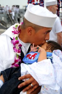 US Navy 090423-N-9758L-256 Boatswain's Mate 2nd Class Roberto Bonilla, assigned to the Arleigh Burke-class guided-missile destroyer USS Hopper (DDG 70), kisses his newborn son after returning from a three-month deployment photo