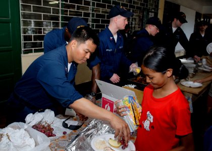 US Navy 090424-N-9520G-181 Aviation Support Equipment Technician 2nd Class Phil Y. Degracia, from Downey, Calif. assigned to the amphibious assault ship USS Essex (LHD 2), serves fruit to students at Banicain Elementary School