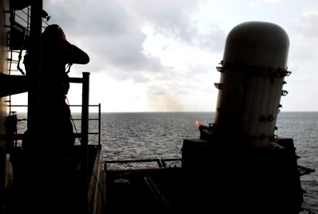 US Navy 090430-N-9928E-001 Fire Controlman 2nd class Jared Mendoza, from Langley, Wash., talks on a sound-powered phone as a Close-In Weapons System fires during a live fire exercise on the fantail aboard the Nimitz-class aircr