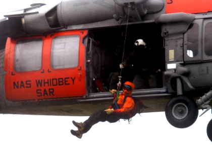 US Navy 090505-N-9860Y-004 Naval Aircrewman 1st Class Chad Lewis, assigned to Naval Air Station Whidbey Island Search and Rescue, guides a Bellingham Mountain Rescue Council volunteer during hoist rescue operations training