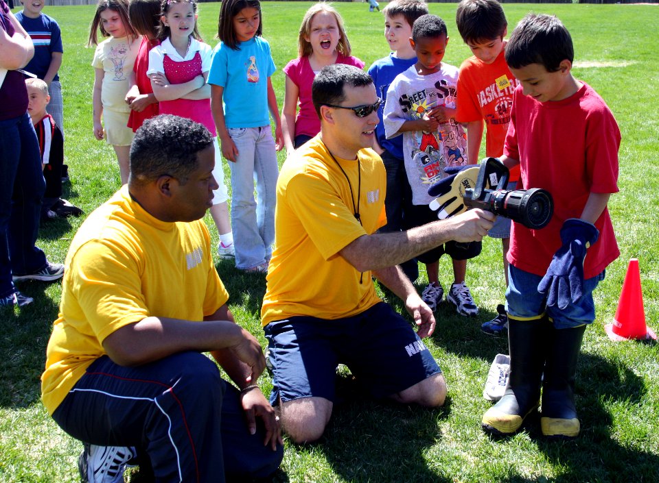 US Navy 090506-N-3038C-443 Navy Cryptologic Technicians 1st Class Eddie Phillips and Robert Zimmerman, both assigned to Navy Information Operations Command, Buckley Air Force Base, Aurora, Colo., help a Clyde Miller Elementary