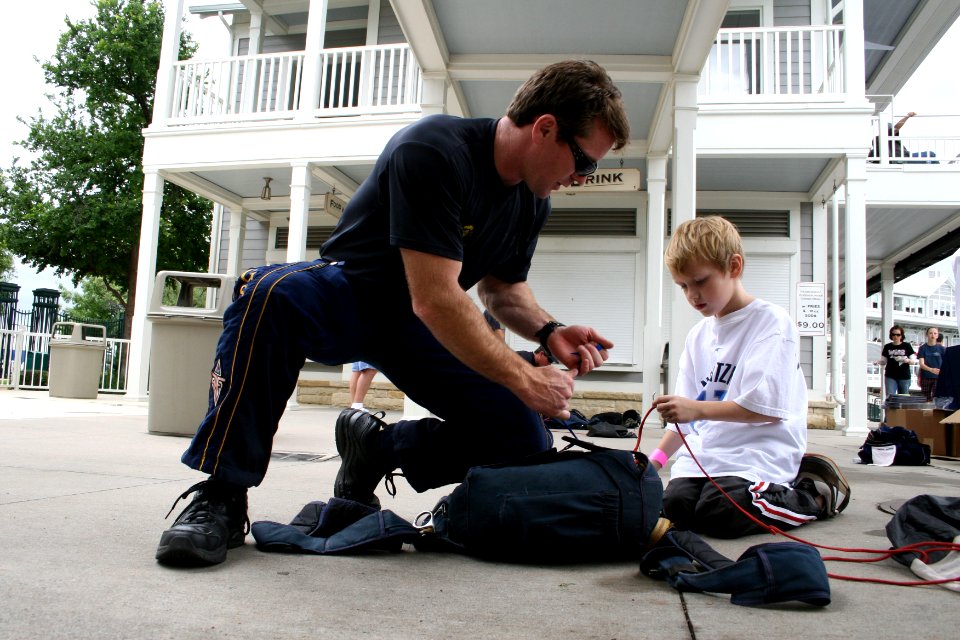 US Navy 090506-N-5366K-080 Chief Special Warfare Operator (SEAL) Justin Gauny, assigned to the U.S. Navy Parachute Team the Leap Frogs, shows a child how to pack his parachute after the team jumped into Dr. Pepper Ball Park