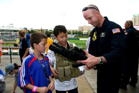 US Navy 090506-N-5366K-049 Lt. Cmdr. Robert Kaminski, assigned to the U.S. Navy Parachute Team the Leap Frogs shows children a display M-4 assault rifle at Dr. Pepper Ball Park after the team parachuted into the park photo