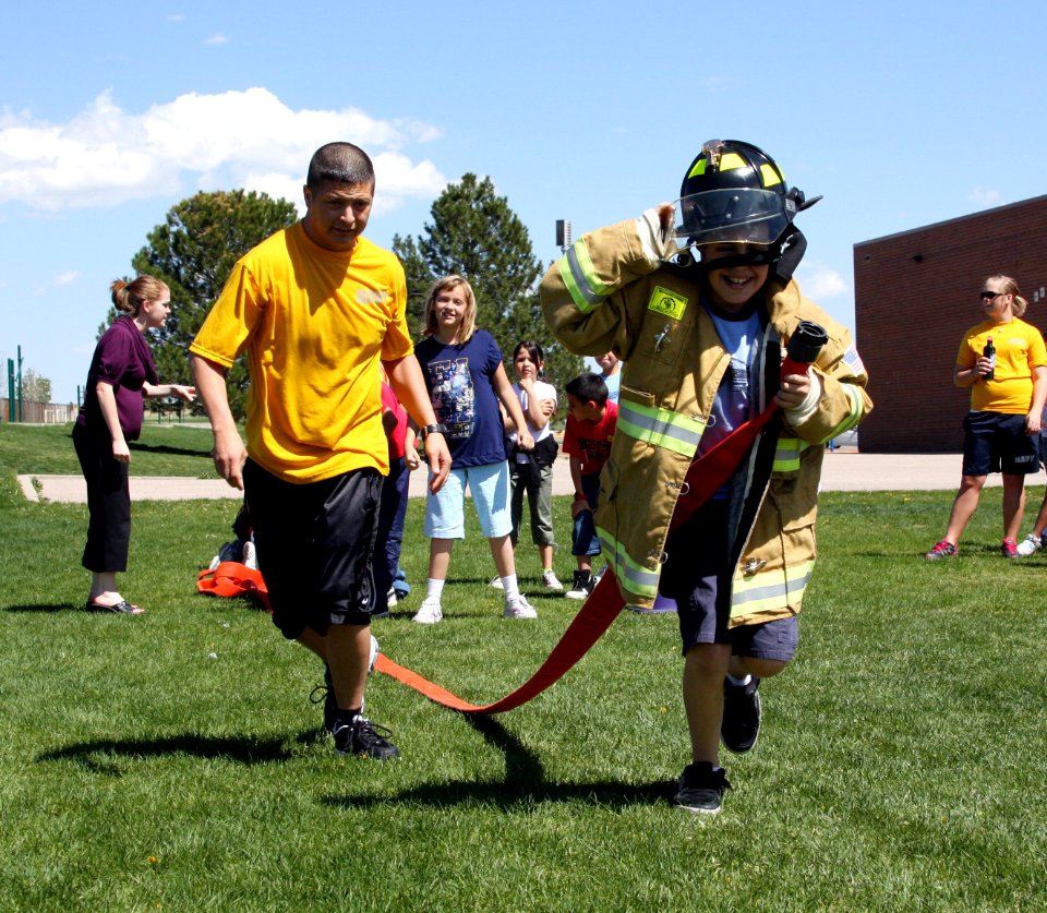 US Navy 090506-N-3038C-438 Navy Cryptologic Technician Technical First Class Ryan Candelaria cheers on a Clyde Miller Elementary School student during a Denver Navy Week firefighting relay