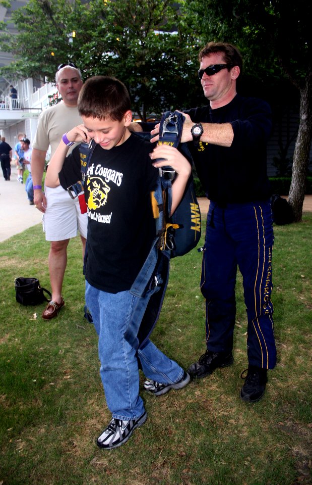 US Navy 090508-N-5366K-030 Chief Special Warfare Operator (SEAL) Justin Gauny, assigned to the U.S. Navy Parachute Team the Leap Frogs, helps a child try on his parachute after the team jumped into Dr. Pepper Ball Park in Frisc