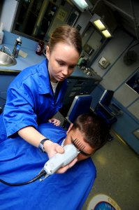 US Navy 090513-N-3946H-014 PACIFIC OCEAN (May 13, 2009) Ship's Serviceman Seaman Kayley Fogarty gives Aviation Warfare Systems Operator 2nd Class Jonathan Hampton a haircut in the enlisted barber shop aboard photo