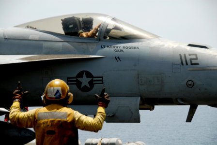 US Navy 090508-N-9909C-058 GULF OF OMAN (May 8, 2009) A shooter uses flight deck hand signals to provide information to a Strike Fighter Squadron (VFA) 143 pilot on the flight deck of aircraft carrier USS Dwight D. Eisenhower (