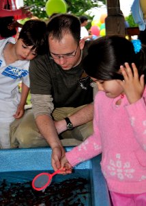 US Navy 090516-N-2013O-035 Aviation Electronics Technician 2nd Class Edward Mason, from Atlanta, tries to catch goldfish with his son and daughter during the USO Military Family Appreciation Carnival at Fleet Activities Yokosuk