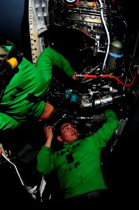 US Navy 090518-N-3946H-044 Aviation Machinist's Mate 2nd Class Norland Obillo and Aviation Machinist's Mate 3rd Class David Carbajal install a fuel line in the engine of an F-A-18F Super Hornet