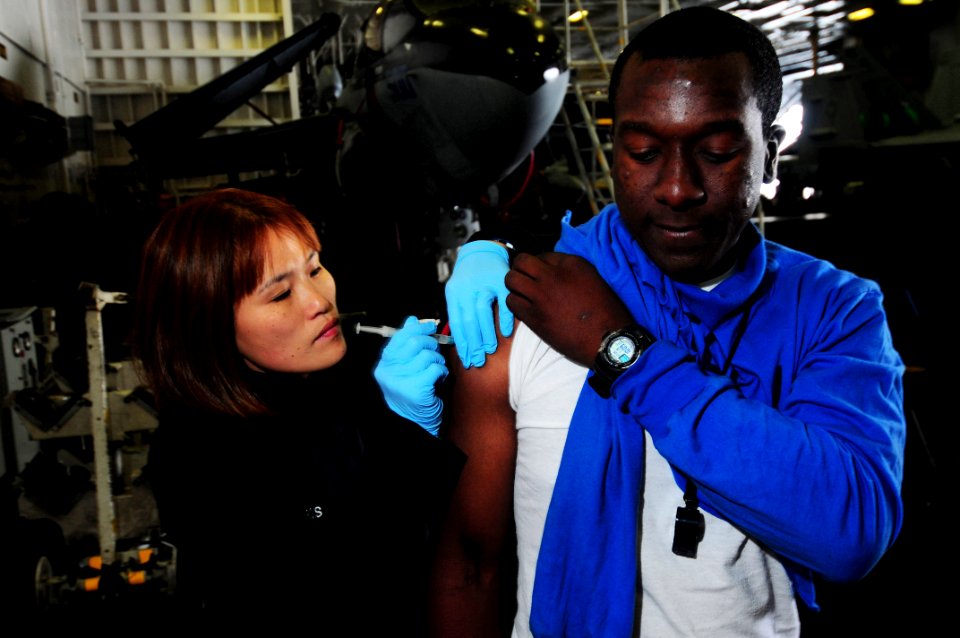 US Navy 090518-N-3946H-016 Hospital Corpsman 2nd Class Jennifer Ross administers an anthrax vaccination to Aviation Boatswain's Mate (Handling) Airman Michael Glover in the hangar bay of the aircraft carrier USS Nimitz (CVN 68)