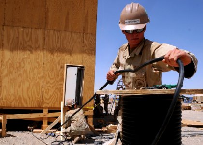 US Navy 090515-N-9410R-061 Construction Electrician Constructionman Benjamin Gerstenmaier, assigned to Naval Mobile Construction Battalion (NMCB) 5, unspools electrical cable
