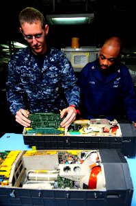 US Navy 090521-N-3946H-002 Aviation Electronics Technician 3rd Class Christopher Retzlaff and Aviation Electronics Technician 3rd Class Michael Carthen inspect a circuit board from the digital display indicator of an F-A-18 Hor photo