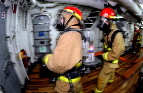 US Navy 090519-N-7280V-046 Machinery Repairman 2nd Class Jeanette Morales and Damage Controlman 2nd Class Robert Lawson standby as part of a back-up hose team during a main space fire drill photo