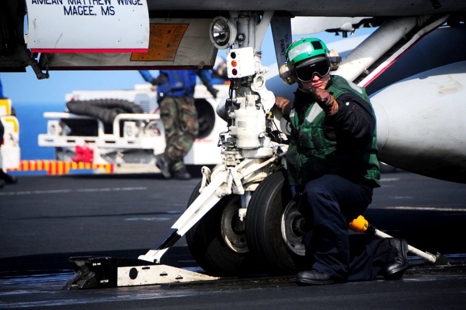US Navy 090519-N-3946H-068 Aviation Boatswain's Mate (Equipment) 2nd Class Juan Anguiano inspects the launch and holdback bar on an F-A-18C Hornet