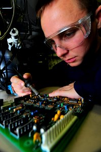 US Navy 090521-N-3946H-012 Aviation Electronics Technician 3rd Class Bernardo Slovinski repairs solder points on the integrated circuit board of an EA-6B Prowler