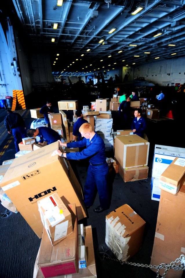 US Navy 090522-N-3946H-079 Supply Department personnel sort boxes of mail and supplies during a carrier onboard delivery in the hangar bay of the aircraft carrier USS Nimitz (CVN 68)