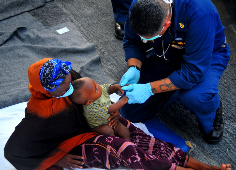 US Navy 090524-N-4774B-133 Chief Hospital Corpsman Joe Gallardo assists a 7-month-old Somali migrant and his mother aboard the guided-missile cruiser USS Lake Champlain (CG 57) after they were rescued from a disabled skiff
