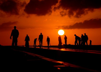 US Navy 090521-N-3885H-029 Sailors assigned to the Air Department of the aircraft carrier USS George H.W. Bush (CVN 77) are silhouetted against the setting sun at the conclusion of flight operations photo