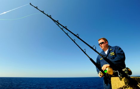 US Navy 090525-N-5345W-128 Lt. Matt Miller, the Dental Officer aboard the amphibious dock landing ship USS Fort McHenry (LSD 43), checks his lines while fishing from the ship's fantail during a Memorial Day steel beach picnic