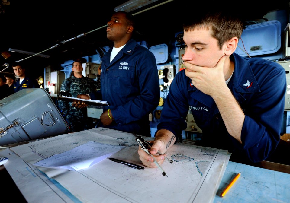 US Navy 090523-N-5345W-336 Quartermaster 3rd Class Devin Harrington, right, plots the course of the amphibious dock landing ship USS Fort McHenry (LSD 43) on a nautical chart in the pilothouse during an underway replenishment