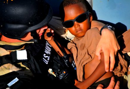 US Navy 090524-N-4774B-079 A member of the visit, board, search, and seizure team carries a five-year-old Somali migrant to the guided-missile cruiser USS Lake Champlain (CG 57) after being rescued from a disabled skiff photo