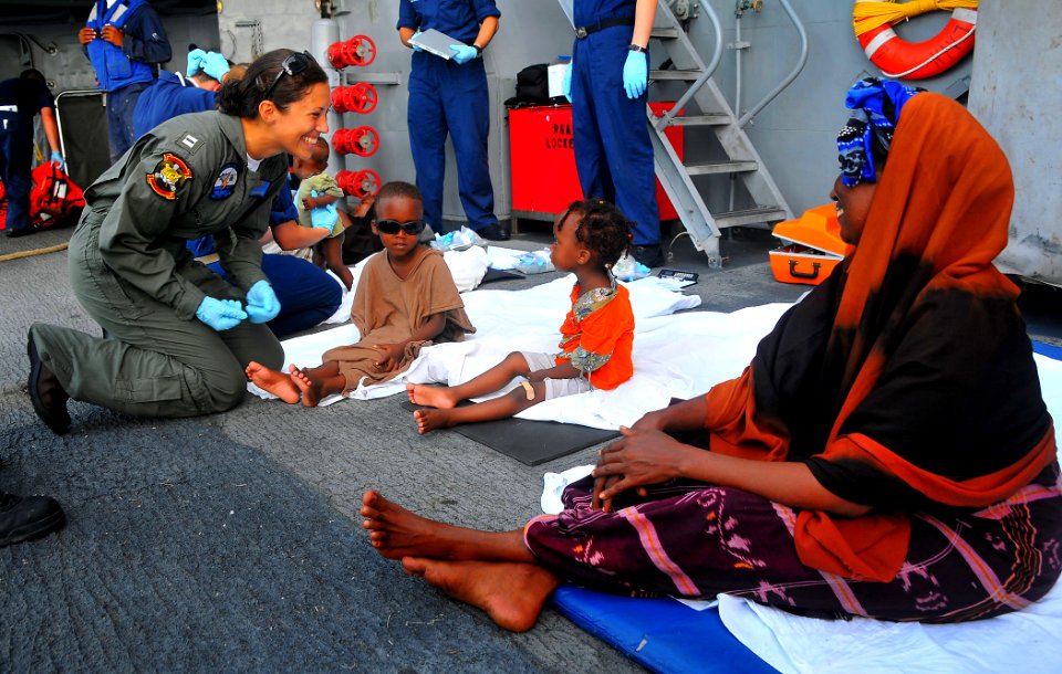 US Navy 090524-N-4774B-097 Lt. Katherine Scholz, the air operations officer for Helicopter Anti-Submarine Squadron Light (HSL) 45, detachment Four, assists Somali migrants aboard the guided-missile cruiser USS Lake Champlain (C