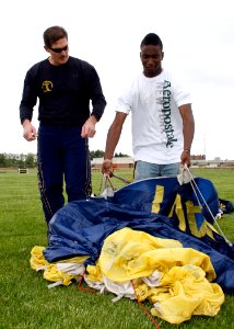 US Navy 090528-N-5366K-050 Chief Special Warfare Operator (SEAL) William Davis, assigned to the U.S. Navy Parachute Team the Leap Frogs, shows a student how to pack his parachute after parachuting into F.J. Turner High School i