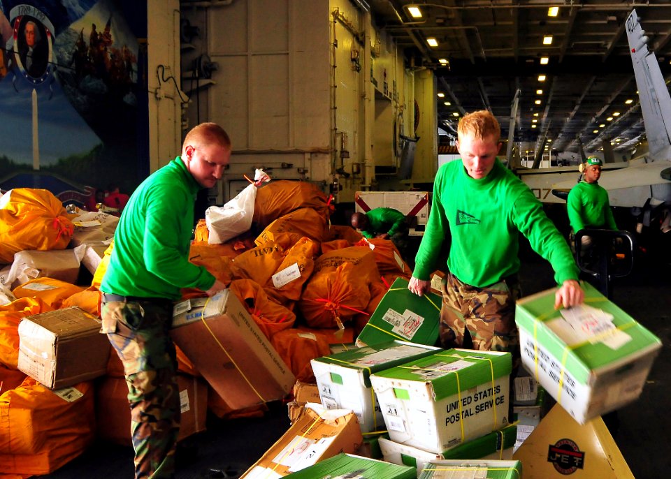 US Navy 090530-N-6233C-038 Postal Clerk 2nd Class Kent Landis and Postal Clerk Seaman Jeremy Fleming sort more than 3,000 pounds of mail in the hangar bay of the aircraft carrier USS George Washington (CVN 73)