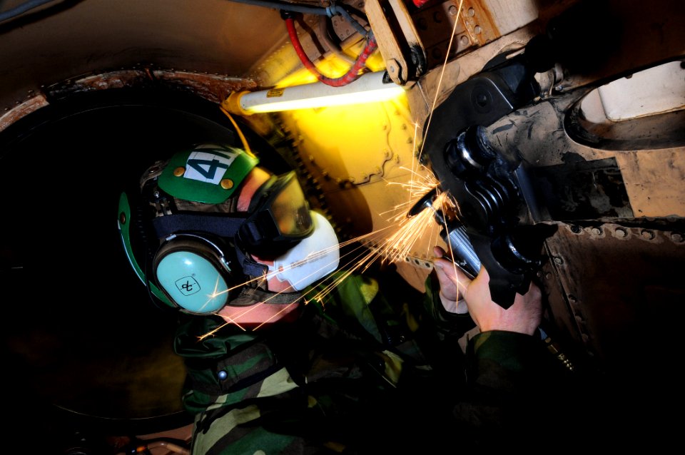 US Navy 090528-N-3946H-021 Aviation Structural Mechanic 2nd Class Ryan Van Zantan grinds corrosion off of the airframe of an F-A-18C Hornet