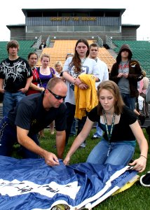 US Navy 090602-N-5366K-009 James Woods, a retired Navy SEAL assigned to the U.S. Navy Parachute Team, the Leap Frogs, shows students how to pack his parachute after the Team gave a parachute demonstration at Brooke High School photo