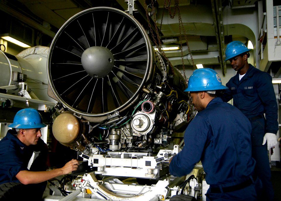 US Navy 090530-N-6720T-037 Aviation Machinist's Mate Airman Johnathan Anderson, left, Aviation Machinist's Mate Howard Quintus and Aviation Machinist's Mate Matthew Mihali transfer an F-A-18 engine to a transport trailer