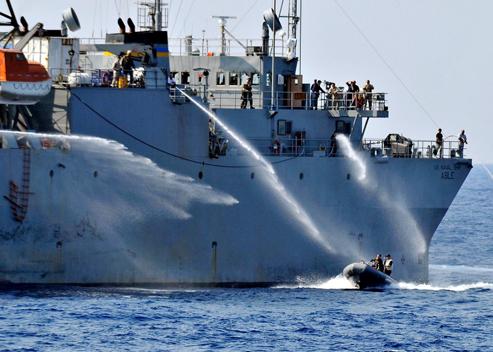 US Navy 090531-N-2638R-003 Personnel aboard the Military Sealift Command ocean surveillance ship USNS Able (T-AGOS 20) use fire fighting hoses to deter simulated attackers in a rigid hull inflatable boat