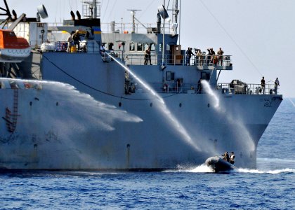 US Navy 090531-N-2638R-003 Personnel aboard the Military Sealift Command ocean surveillance ship USNS Able (T-AGOS 20) use fire fighting hoses to deter simulated attackers in a rigid hull inflatable boat