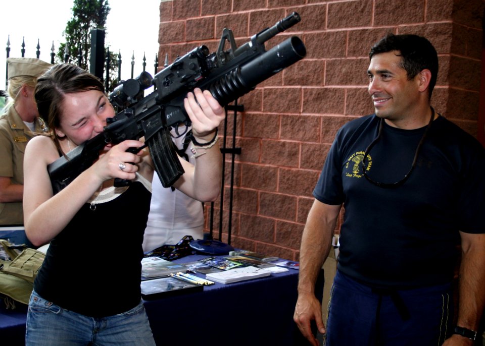 US Navy 090602-N-5366K-052 Special Warfare Operator 1st Class (SEAL) Robert Darakjy, assigned to the U.S. Navy Parachute Team the Leap Frogs, shows a display M-4 assault rifle to a Washington Wild Things baseball fan