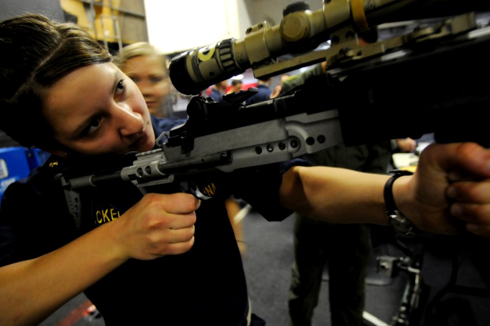 US Navy 090609-N-3610L-618 Midshipman Kaitlyn Hackel tests the weight of an Enhanced Battle Rifle (EBR) during an Explosive Ordnance Disposal (EOD) Technician demonstration in the hangar bay of the aircraft carrier USS Ronald R