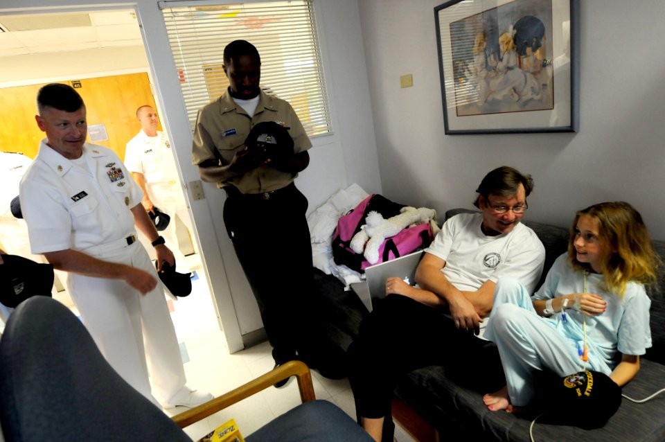 US Navy 090610-N-9818V-396 Master Chief Petty Officer of the Navy (MCPON) Rick West and Missile Technician 3rd Class Rodney Edwards gives a patient and her father a Navy ball cap during a Caps for Kids visit