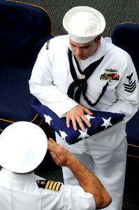 US Navy 090609-N-3610L-458 Capt. K.J. Norton, commanding officer of the aircraft carrier USS Ronald Reagan (CVN 76), salutes Boatswain's Mate 1st Class Noel Myers during a burial at sea ceremony aboard Ronald Reagan photo