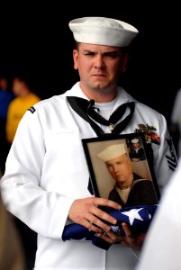 US Navy 090609-N-9132C-329 Boatswain's Mate 1st Class Noel Myers holds a photo of his father, Edmond McKinley Myers Jr., and a flag moments after a burial at sea ceremony aboard the aircraft carrier USS Ronald Reagan (CVN 76)