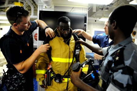US Navy 090611-N-5242D-231 Damage Controlman 1st Class James Harry, Damage Controlman Fireman Jason King and Djiboutian Navy Sublieutenant Moussa Hanfare help Djiboutian Navy Cpl. Abdoullauder Issa don a fire-fighting ensemble
