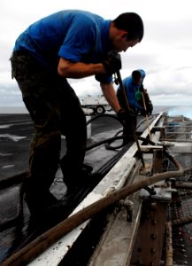 US Navy 090612-N-7780S-040 Aviation Boatswain's Mate (Handling) Airman Nehemiah Ulibarri and Aviation Boatswain's Mate (Handling) Nicholas Aguilar scrub flight deck scupper drains aboard the Nimitz-class aircraft carrier USS Jo