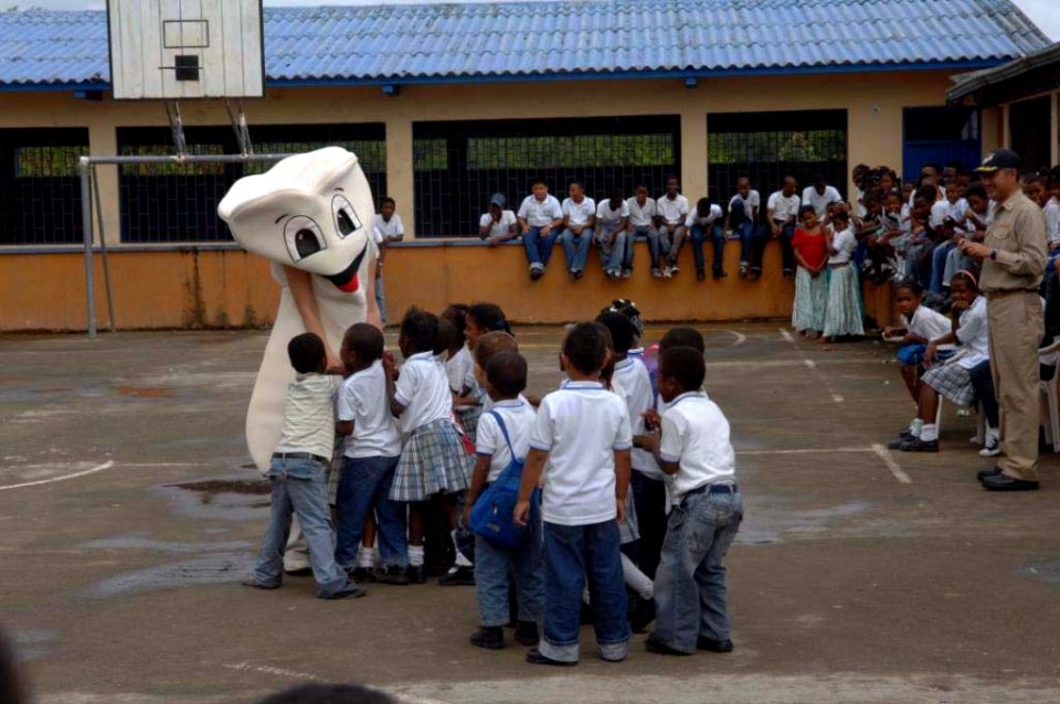 US Navy 090610-F-1333S-024 Colombian children gather around the USNS Comfort dental mascot as the ship's dental team and the U.S. Air Force South Band bring music and dental health care education to Cuidadela Mixtra Escuela