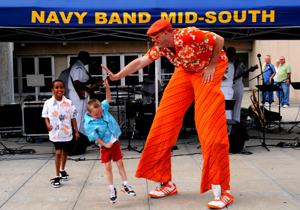 US Navy 090613-N-3750S-403 Rex Campbell, known as Orange Rex, a local entertainer, dances with children during the Yard Dawgz Game Block Party at the Cox Convention Center