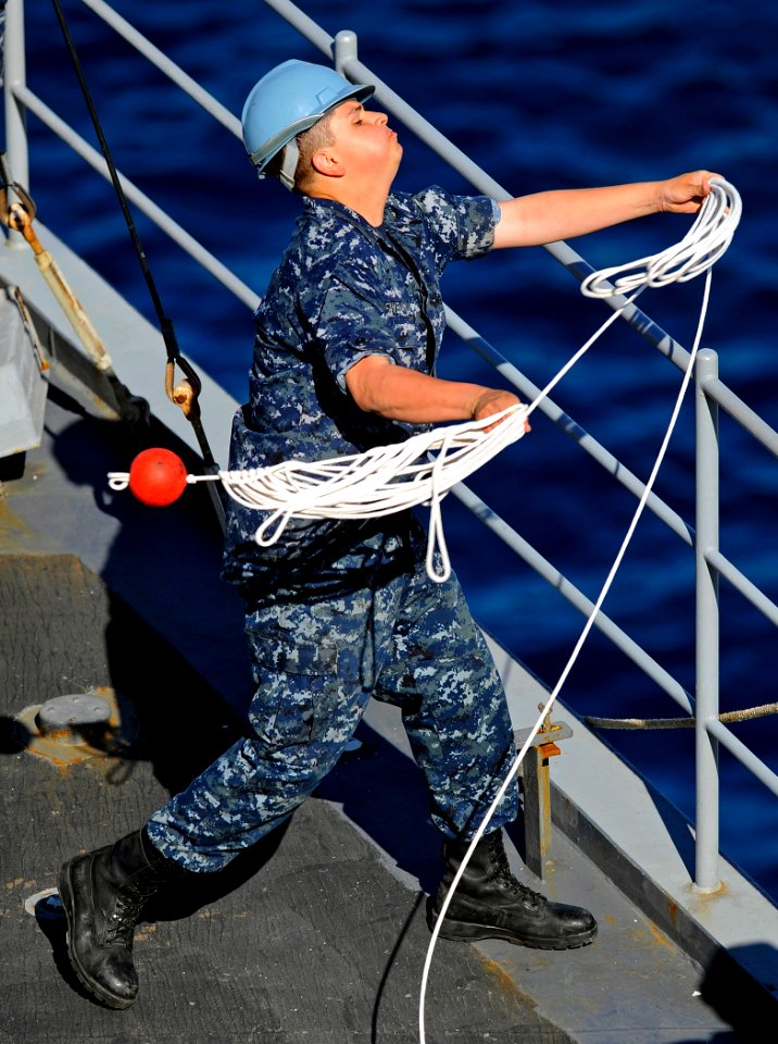 US Navy 090612-N-5345W-047 Deck department Seaman Jose Favela tosses a heaving line from the foc'sle of the amphibious dock landing ship USS Fort McHenry (LSD 43) as the ship moors pier side in Souda Bay, Greece